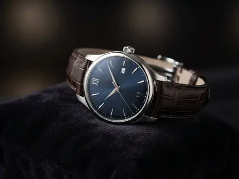 An elegant dress wristwatch with a deep blue dial, Roman numerals and a brown leather strap resting on dark velvet